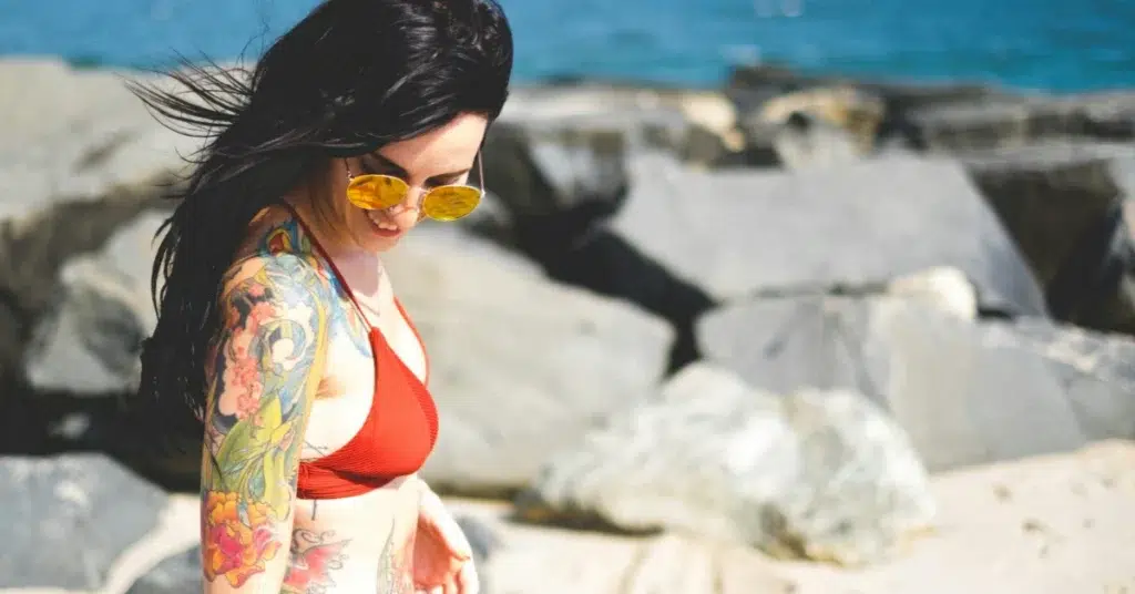 A beautiful girl with tattoos walks on the beach